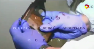 Uno de los peritos aparece en el video limpiando el arma con papel higiénico para buscar su información. (Crédito: YouTube/PeriodismoParaTodos)