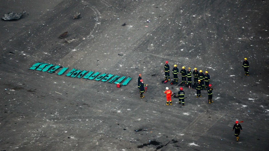 Rescuers are seen at the site of the massive explosions in Tianjin on August 13, 2015. Enormous explosions in a major Chinese port city killed at least 44 people and injured more than 500, state media reported on August 13, leaving a devastated industrial landscape of incinerated cars, toppled shipping containers and burnt-out buildings. CHINA OUT AFP PHOTO (Photo credit should read STR/AFP/Getty Images)
