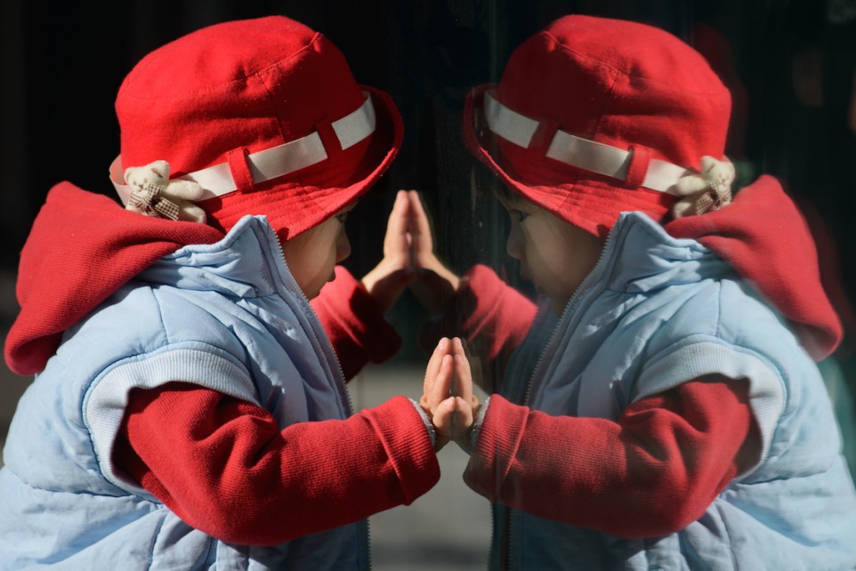 A child looks at his reflection in a window in Beijing on November 17, 2013. On November 15 China's Communist rulers announced an easing of the country's controversial one-child policy as part of a raft of sweeping pledges including the abolition of its "re-education" labour camps and loosening controls on the economy. AFP PHOTO / Ed Jones (Photo credit should read Ed Jones/AFP/Getty Images)