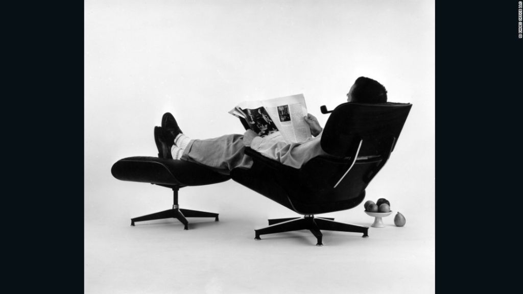 Charles Eames en la silla y otomana de madera contrachapada. Fotografía para un anuncio publicitario, 1956. 