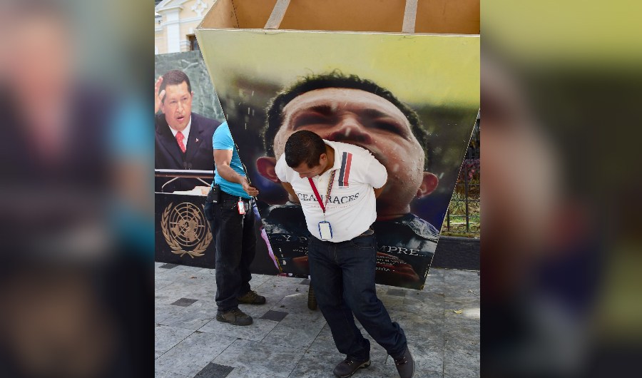 A National Assembly employee helps to remove from the building a picture of late President Hugo Chavez, in Caracas on January 6, 2016. Venezuela's opposition on Tuesday broke the government's 17-year grip on the legislature and vowed to force out President Nicolas Maduro despite failing for the time being to clinch its hoped-for 'supermajority.' AFP PHOTO/RONALDO SCHEMIDT / AFP / RONALDO SCHEMIDT (Photo credit should read RONALDO SCHEMIDT/AFP/Getty Images)