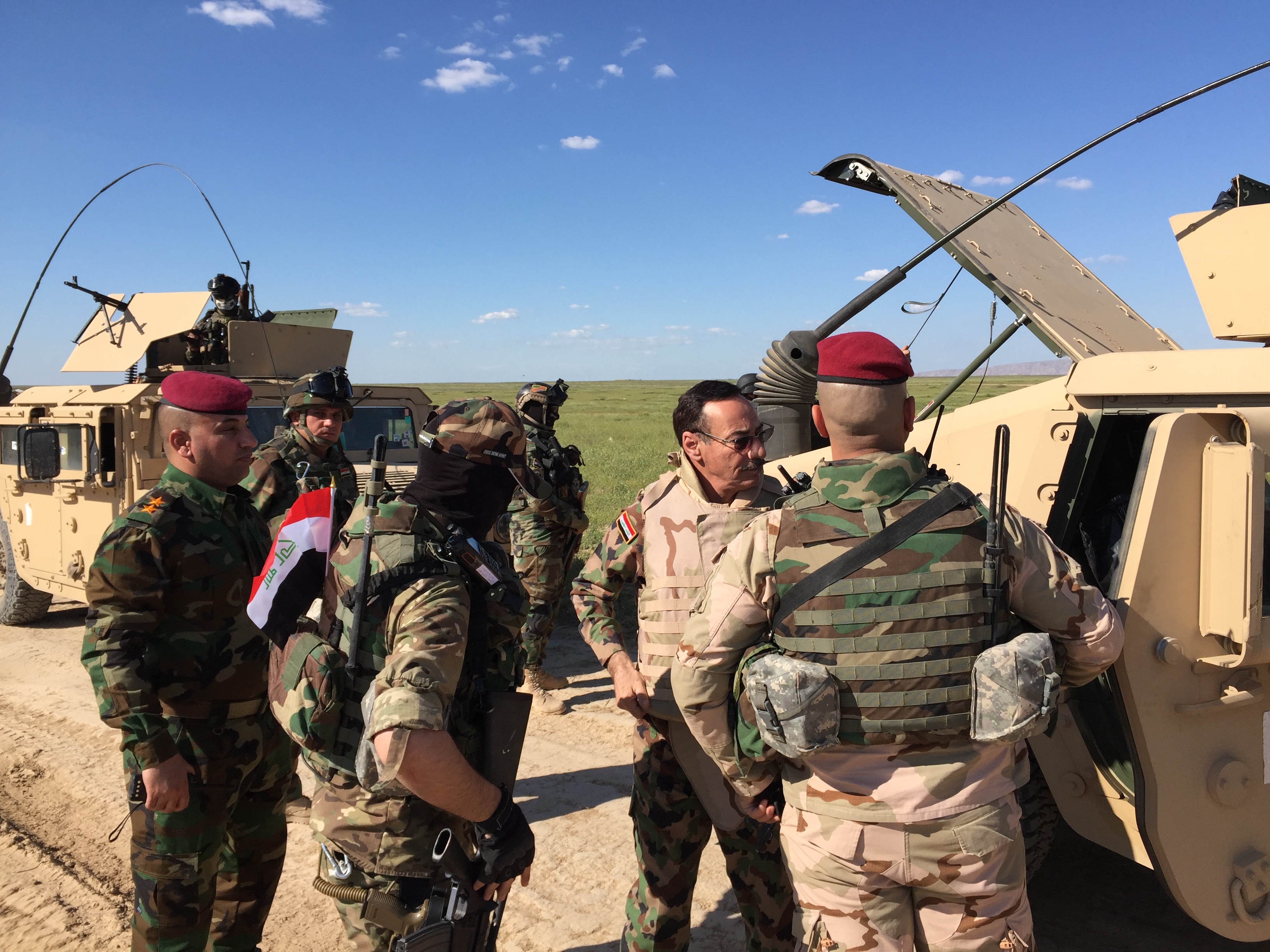 El Comandante General, Najim al-Jobori (que usa gafas de sol) se pone el chaleco antibalas mientras que su equipo se dirige hacia el frente. 