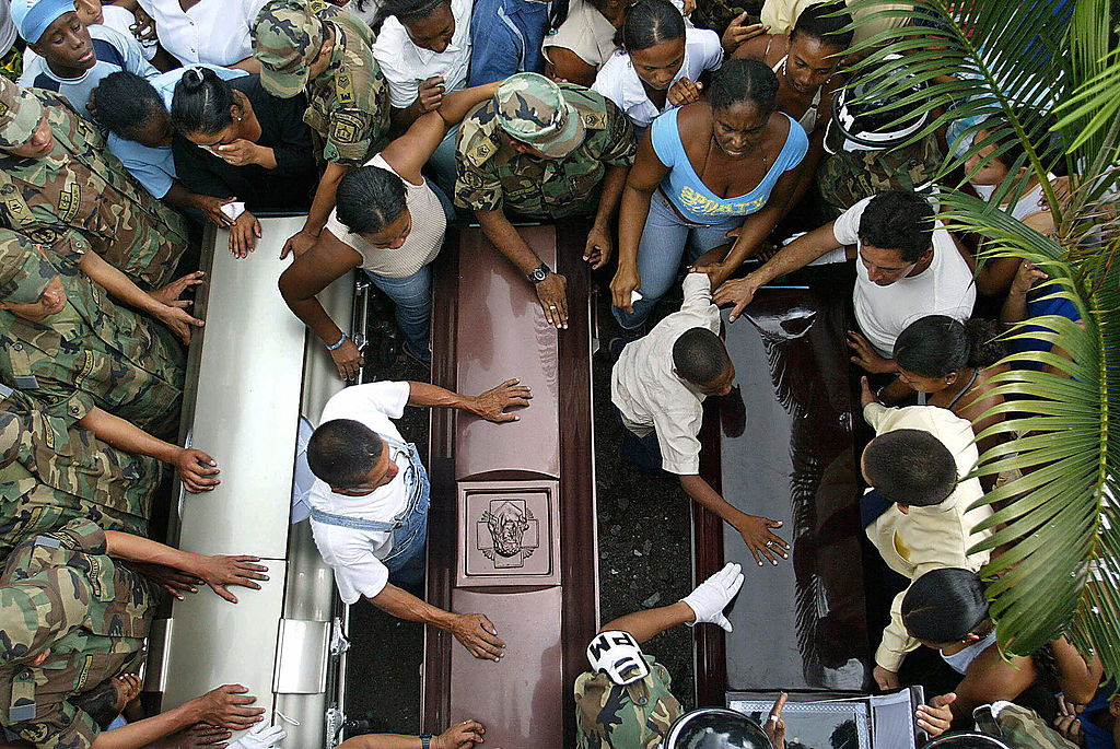 PAZ RECONCILIACIÓN FARC CAREPA, COLOMBIA: Relatives moan next to the coffins of soldiers Luis Adan Hoyos, Luis Alberto Benites and Emilon Rodriguez, during their wake in Carepa, Colombia, 11 February 2005. At least 19 soldiers were murdered during fightings against the Colombian Revolutionary Armed Forces (FARC) guerrillas. AFP PHOTO/Gerardo GOMEZ (Photo credit should read GERARDO GOMEZ/AFP/Getty Images)