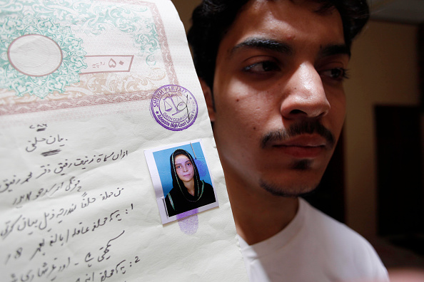 Hassan Khan muestra un documento con una fotografía de su esposa (Crédito: STR/AFP/Getty Images)