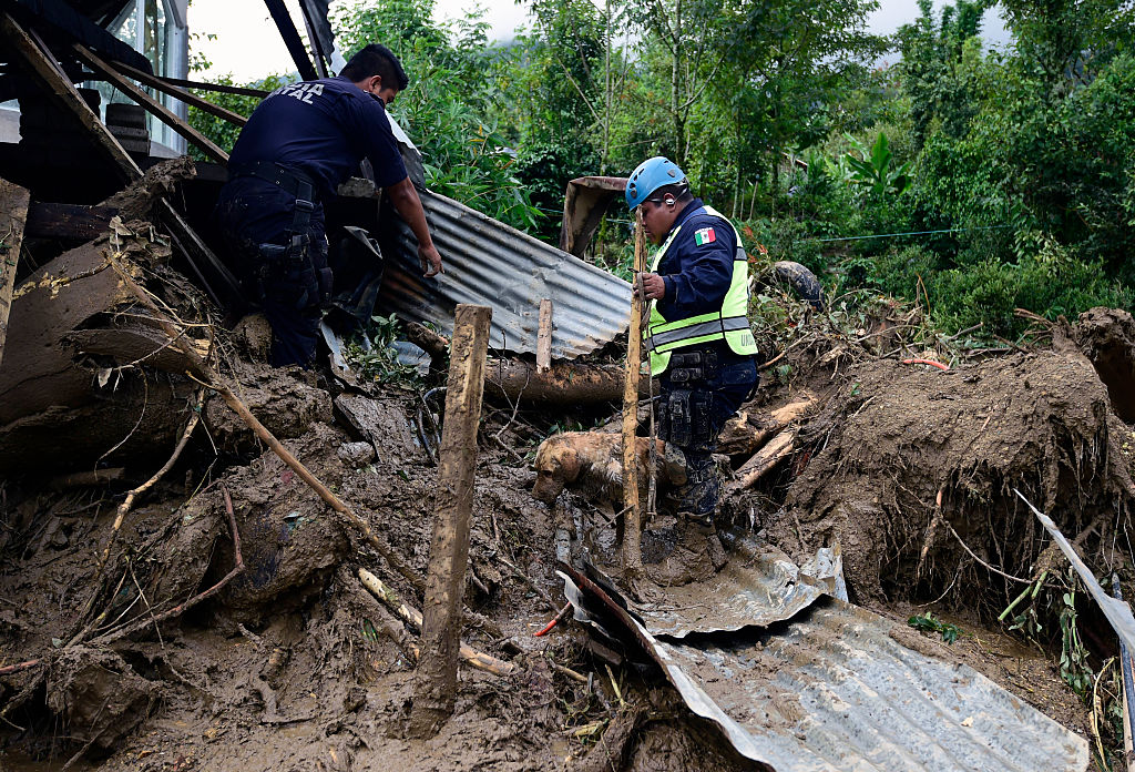 A Federal Police rescuer and his sniffer dog search for buried corpses amid the damage caused by a landslide ensuing the passage of Tropical Storm Earl in the community of Xaltepec, Puebla state, eastern Mexico on August 8, 2016. A total of 29 people died in the communities of Xaltepec, Tlaola and Huauchinango in the Mexican state of Puebla after their homes were buried by landslides following heavy rains from Earl, which reached Mexican territory on Thursday as a tropical storm and Saturday was only a remnant low pressure. / AFP / AE / ALFREDO ESTRELLA (Photo credit should read ALFREDO ESTRELLA/AFP/Getty Images)