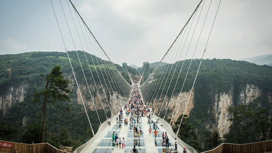 Visitors cross the world's highest and longest glass-bottomed bridge above a valley in Zhangjiajie in China's Hunan Province on August 21, 2016. / AFP / FRED DUFOUR (Photo credit should read FRED DUFOUR/AFP/Getty Images)