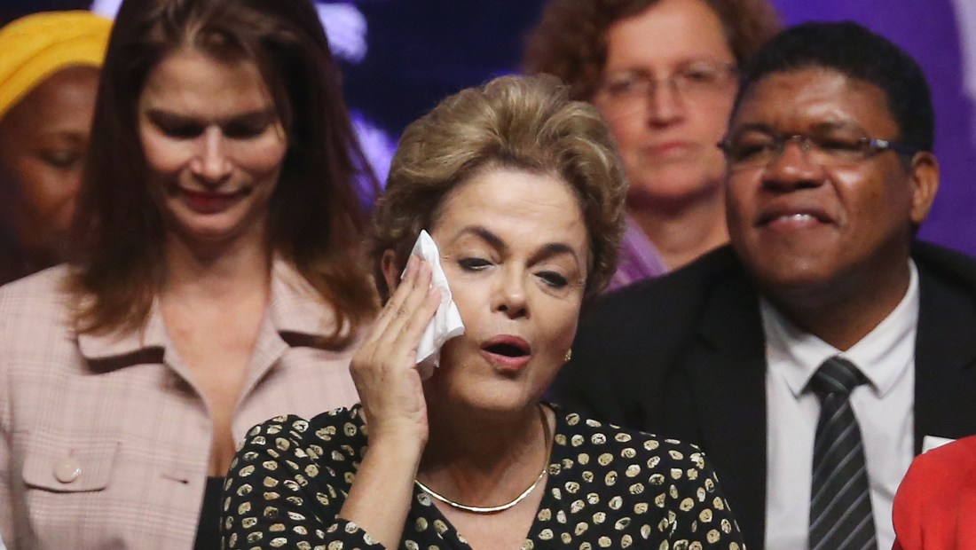 BRASILIA, BRAZIL - MAY 10: Embattled Brazilian President Dilma Rousseff (C) wipes her face with a handkerchief after speaking at a women's rights conference on May 10, 2016 in Brasilia, Brazil. Rousseff is facing an impeachment vote in the Senate tomorrow that could force her to step down from the presidency for 180 days and face trial. (Photo by Mario Tama/Getty Images)