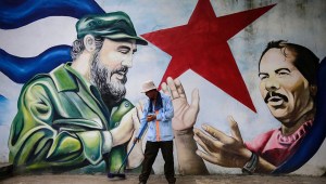 TOPSHOT - A municipal worker sweeps the floor in front of a mural depicting Cuban revolutionary leader Fidel Castro (L) and Nicaraguan President Daniel Ortega at Cuba square in Managua on November 26, 2016, the day after Castro died. Cuban revolutionary leader Fidel Castro has died aged 90, prompting mixed grief and joy Saturday along with international tributes for the man whose iron-fisted rule defied the United States for half a century. / AFP / INTI OCON (Photo credit should read INTI OCON/AFP/Getty Images)