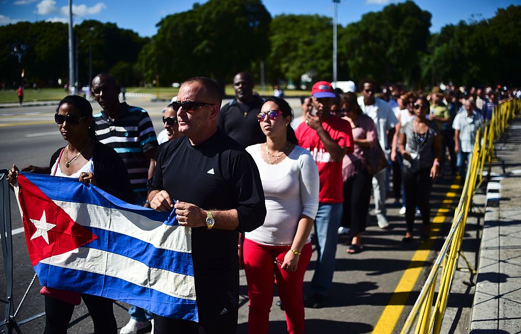 People holding a Cuban national flag queue to enter Jose Marti's memorial to pay their last respects to Cuban revolutionary icon Fidel Castro at Revolution Square in Havana, on November 28, 2016. A titan of the 20th century who beat the odds to endure into the 21st, Castro died late Friday after surviving 11 US administrations and hundreds of assassination attempts. No cause of death was given. Castro's ashes will go on a four-day island-wide procession starting Wednesday before being buried in the southeastern city of Santiago de Cuba on December 4. / AFP / RONALDO SCHEMIDT (Photo credit should read RONALDO SCHEMIDT/AFP/Getty Images)