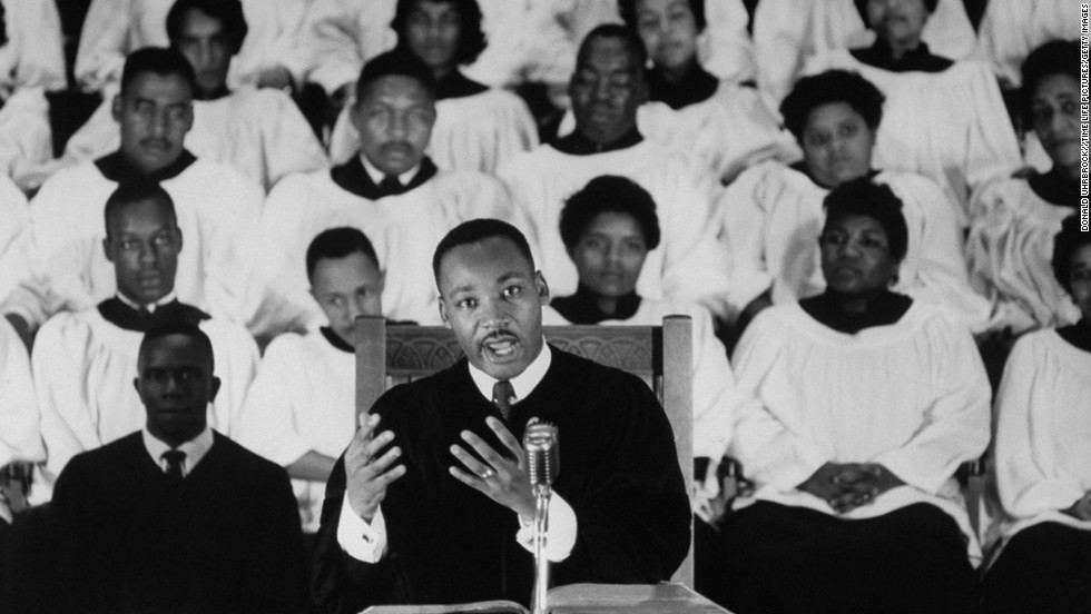 Civil Rights activist Rev. Dr. Martin Luther King Jr. standing at pulpit delivering his sermon as a white-robed choir listens in the bkgd. at Ebenezer Baptist Church. (Photo by Donald Uhrbrock//Time Life Pictures/Getty Images)