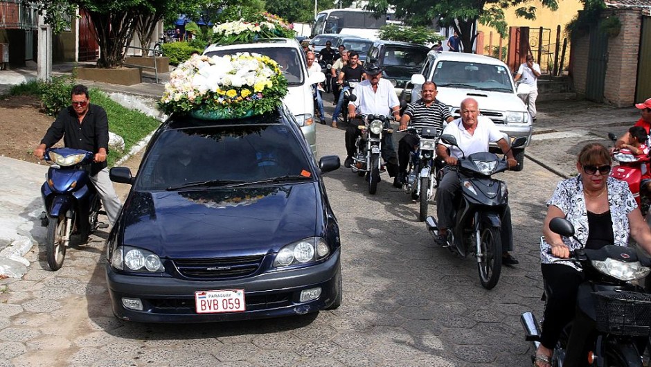 Locals accompany the funerl cortege of Paraguayan late football star Roberto Cabanas during his funeral in Pilar, Paraguay, on January 10, 2017. The striker -who died of a heart attack on the eve, aged 55- was a hero of top Argentine league side Boca Juniors and played alongside Brazilian legend Pele for the New York Cosmos in the 1980s. / AFP / STR (Photo credit should read STR/AFP/Getty Images)