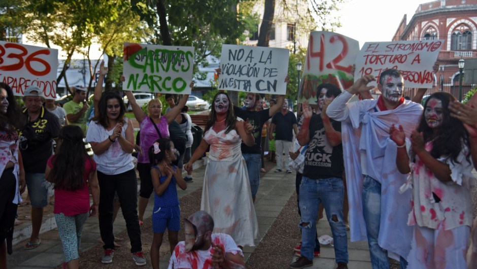 People hold a demonstration in the center of Asuncion on February 3, 2017 to protest the campaign by President Horacio Cartes' supporters in the governing Colorado Party to collect signatures seeking a constitutional reform with the aim of pushing for presidential reelection, which is banned by the constitution. Many of the demonstrators dressed as zombies, in the style of the popular series "The Walking Dead", to mock the appearance of the names of dead people on the lists of signatures demanding a constitutional reform ahead of the 2018 presidential elections. / AFP / NORBERTO DUARTE (Photo credit should read NORBERTO DUARTE/AFP/Getty Images)