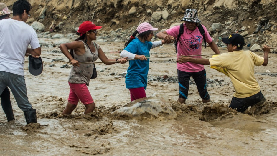 Local residents try to cross a flash flood in Huachipa district, on the east side of Lima, on March 19, 2017. El Nino-fuelled flash floods and landslides hit parts of Lima, where most of the water distribution systems have collapsed due to unusual heavy seasonal downpours and people are facing drinking water shortages. / AFP PHOTO / ERNESTO BENAVIDES (Photo credit should read ERNESTO BENAVIDES/AFP/Getty Images)