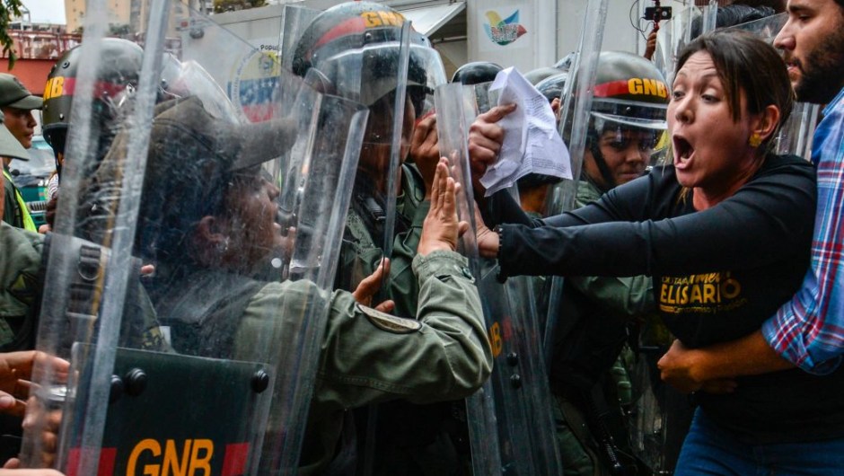 TOPSHOT - Venezuelan opposition deputy Amelia Belisario (2nd-R) scuffles with National Guard personnel in riot gear during a protest in front of the Supreme Court in Caracas on March 30, 2017. Venezuela's Supreme Court took over legislative powers Thursday from the opposition-majority National Assembly, whose speaker accused leftist President Nicolas Maduro of staging a "coup." / AFP PHOTO / JUAN BARRETO (Photo credit should read JUAN BARRETO/AFP/Getty Images)
