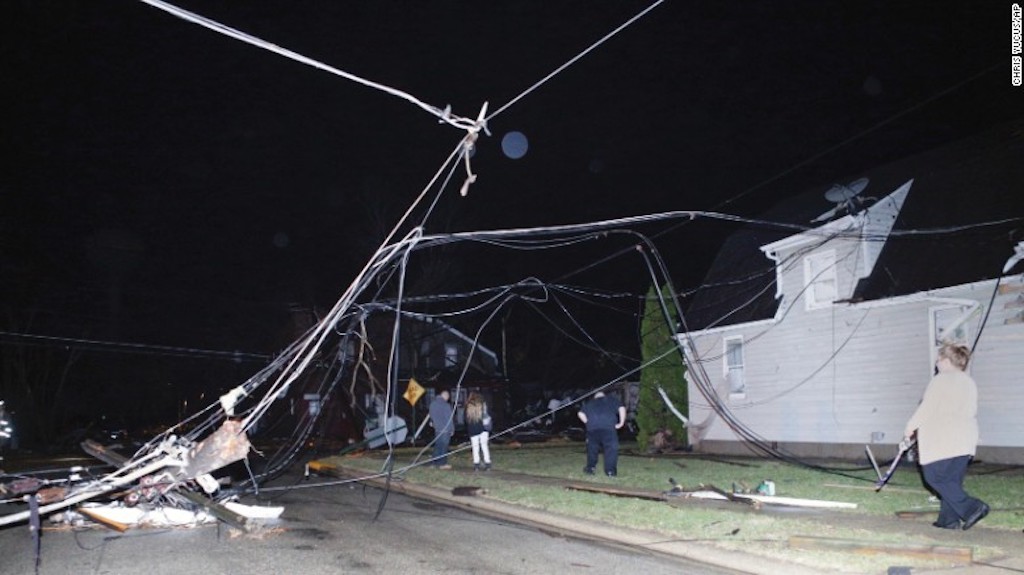 Personas caminan entre cables caídos después de que una tormenta pasara por Naplate, el martes.