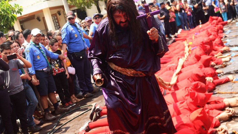 A faithful fancy dressed as Jesus Christ walks over a lying group of masked "talciguines" --characters of the local folklore-- as part of the celebration of an ancient local tradition that marks the start of Holy Week, on April 10, 2017 in Texistepeque, some 83 km west of San Salvador. The talciguines are devils who lash Catholic faithful to cleanse their sins. / AFP PHOTO / Marvin RECINOS (Photo credit should read MARVIN RECINOS/AFP/Getty Images)