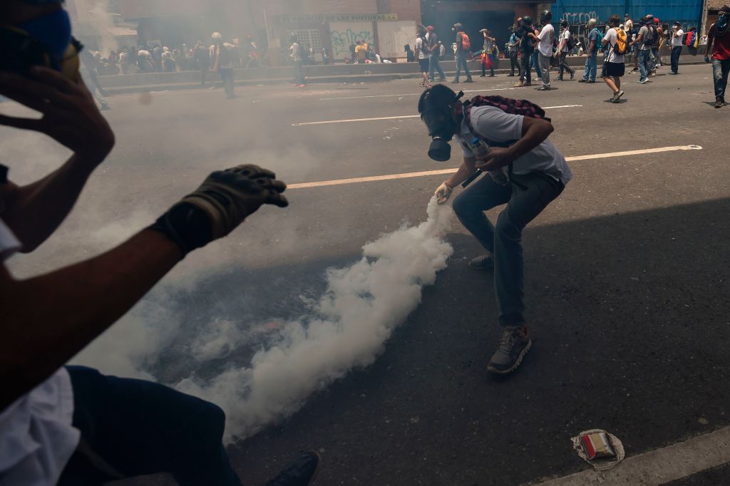 A demonstrator throws a tear gas canister back at the police during a rally against Venezuelan President Nicolas Maduro, in Caracas on April 19, 2017. Venezuela braced for rival demonstrations Wednesday for and against President Nicolas Maduro, whose push to tighten his grip on power has triggered waves of deadly unrest that have escalated the country's political and economic crisis. / AFP PHOTO / Juan BARRETO (Photo credit should read JUAN BARRETO/AFP/Getty Images)