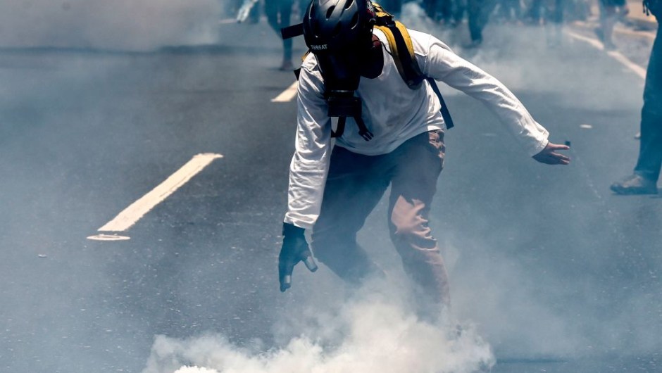 An opposition activist clashes with riot police during a protest against President Nicolas Maduro in Caracas on April 26, 2017. Venezuelan riot police fired tear gas to stop anti-government protesters from marching on central Caracas, the latest clash in a wave of unrest that, up to now, has left 26 people dead. / AFP PHOTO / JUAN BARRETO (Photo credit should read JUAN BARRETO/AFP/Getty Images)