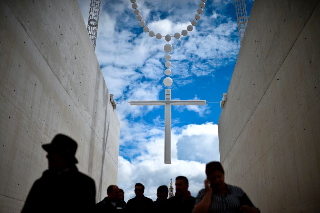People walk under a giant rosary hanging at Fatima Sanctuary in Fatima, central Portugal, on May 12, 2017. Two of the three child shepherds who reported apparitions of the Virgin Mary in Fatima, Portugal, one century ago, will be declared saints on May 13, 2017 by Pope Francis. The canonisation of Jacinta and Francisco Marto will take place during the Argentinian pontiff's visit to a Catholic shrine visited by millions of pilgrims every year. / AFP PHOTO / PATRICIA DE MELO MOREIRA (Photo credit should read PATRICIA DE MELO MOREIRA/AFP/Getty Images)
