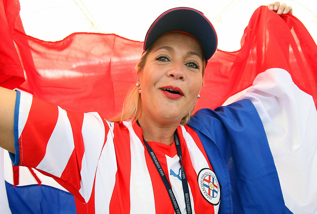 Frankfurt am Main, GERMANY: A Paraguay fan cheers while holding the country's flag at Frankfurt's World Cup Stadium ahead of the first round Group B 2006 World Cup football match between England and Paraguay, 10 June 2006. Paraguay are making their third successive World Cup appearance, and their sixth in total, with their best performances coming in 1986, 1998 and 2002 when they reached the last 16. AFP PHOTO / VALERY HACHE (Photo credit should read VALERY HACHE/AFP/Getty Images)
