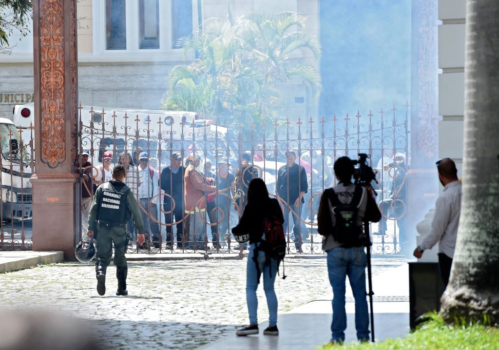 Supporters of Venezuelan President Nicolas Maduro stand at the gate of the National Assembly building in Caracas before storming it on July 5, 2017 as opposition deputies hold a special session on Independence Day. A political and economic crisis in the oil-producing country has spawned often violent demonstrations by protesters demanding President Nicolas Maduro's resignation and new elections. The unrest has left 91 people dead since April 1. / AFP PHOTO / Juan BARRETO (Photo credit should read JUAN BARRETO/AFP/Getty Images)