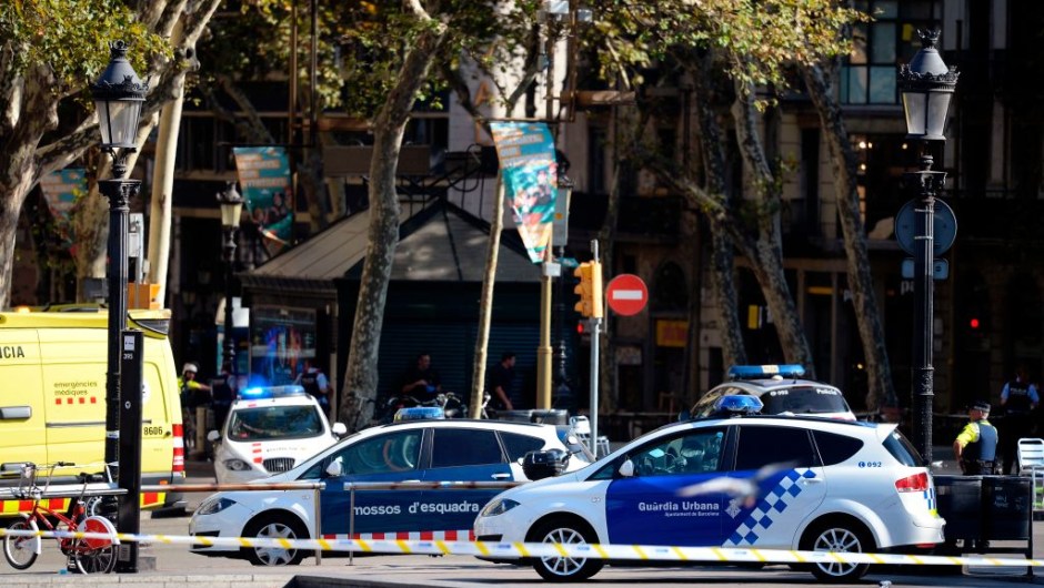 Policemen stand next to vehicles in a cordoned off area after a van ploughed into the crowd, injuring several persons on the Rambla in Barcelona on August 17, 2017. / AFP PHOTO / Josep LAGO (Photo credit should read JOSEP LAGO/AFP/Getty Images)