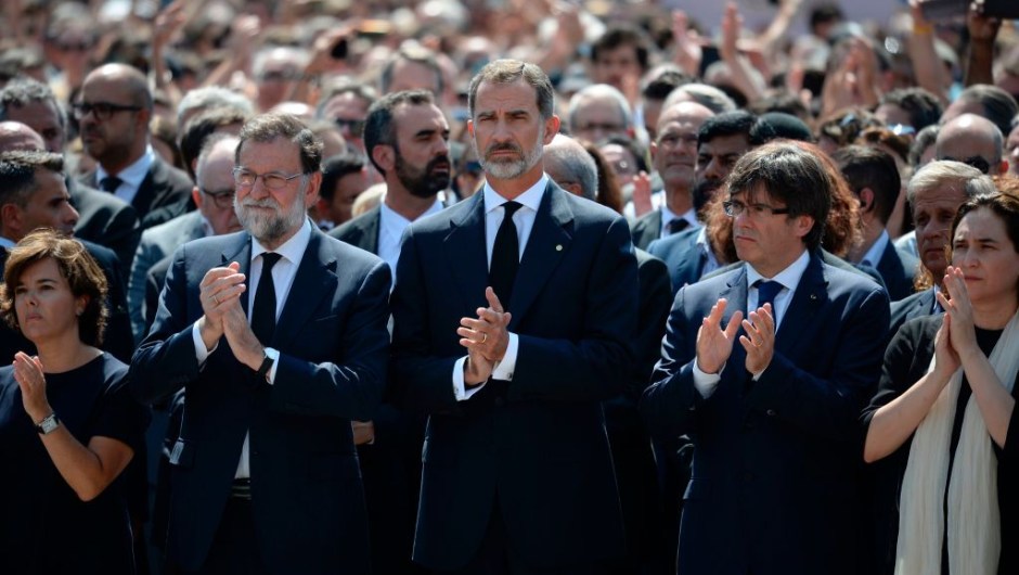 Spain's King Felipe VI (C), Spanish Prime Minister Mariano Rajoy (2ndL), President of Catalonia Carles Puigdemont (2ndR), Spanish vice-President of the Government and Minister of the Presidency and of the Regional Administrations Soraya Saenz de Santamaria (L) and Barcelona's mayor Ada Colau applaud after observing a minute of silence for the victims of the Barcelona attack at Plaza de Catalunya on August 18, 2017, a day after a van ploughed into the crowd, killing 13 persons and injuring over 100 on the Rambla in Barcelona. Drivers have ploughed on August 17, 2017 into pedestrians in two quick-succession, separate attacks in Barcelona and another popular Spanish seaside city, leaving 13 people dead and injuring more than 100 others. In the first incident, which was claimed by the Islamic State group, a white van sped into a street packed full of tourists in central Barcelona on Thursday afternoon, knocking people out of the way and killing 13 in a scene of chaos and horror. Some eight hours later in Cambrils, a city 120 kilometres south of Barcelona, an Audi A3 car rammed into pedestrians, injuring six civilians -- one of them critical -- and a police officer, authorities said. / AFP PHOTO / Josep LAGO (Photo credit should read JOSEP LAGO/AFP/Getty Images)