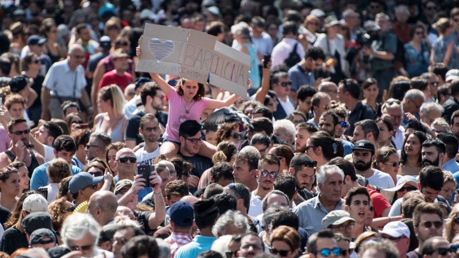 BARCELONA, SPAIN - AUGUST 18: A girl holds up a banner as people gather in Placa de Catalunya to observe a one minute's silence for the victims of yesterday's terrorist attack, on August 18, 2017 in Barcelona, Spain. Fourteen people were killed and dozens injured when a van hit crowds in the Las Ramblas area of Barcelona on Thursday. Spanish police have also killed five suspected terrorists in the town of Cambrils to stop a second terrorist attack. (Photo by Carl Court/Getty Images)