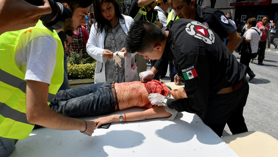 A woman is assisted after being injured during a quake in Mexico City on September 19, 2017. A powerful earthquake shook Mexico City on Tuesday, causing panic among the megalopolis' 20 million inhabitants on the 32nd anniversary of a devastating 1985 quake. The US Geological Survey put the quake's magnitude at 7.1 while Mexico's Seismological Institute said it measured 6.8 on its scale. The institute said the quake's epicenter was seven kilometers west of Chiautla de Tapia, in the neighboring state of Puebla. / AFP PHOTO / Omar TORRES (Photo credit should read OMAR TORRES/AFP/Getty Images)