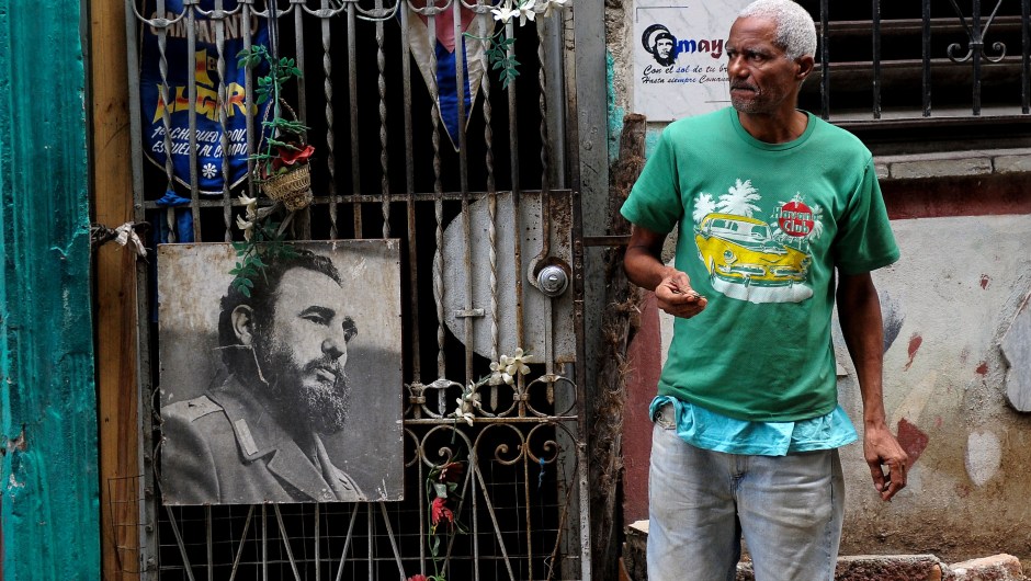 A man stands next to a poster of late Cuban leader Fidel Castro in Havana, on November 24, 2017. Cuba commemorates on November 25 the first anniversary of the death of Fidel Castro, focused on an electoral process that will imply a presidential change, in a framework of economic regression, hostility from the United States, and stagnation in its reforms. / AFP PHOTO / YAMIL LAGE (Photo credit should read YAMIL LAGE/AFP/Getty Images)