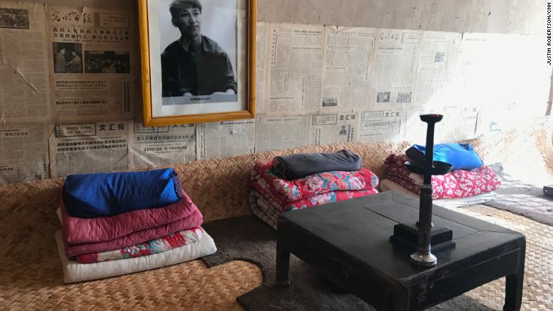 Una foto de un Xi juvenil, así como viejos periódicos, adornan la pared sobre su antigua cama compartida en una "casa cueva".
