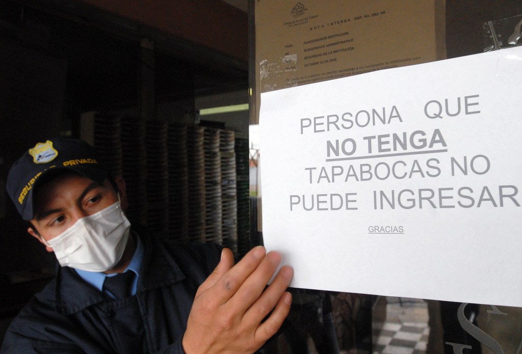 Un miembro de seguridad muestra uno de los carteles que se colgaron en Colombia por la crisis del AH1N1 en 2009. Foto de archivo. (Crédito: LUIS RAMIREZ/AFP/Getty Images)