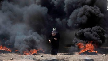 A Palestinian woman walks through black smoke from burning tires during a protest on the Gaza Strip's border with Israel, Monday, May 14, 2018. Thousands of Palestinians are protesting near Gaza's border with Israel, as Israel prepared for the festive inauguration of a new U.S. Embassy in contested Jerusalem. (AP Photo/Khalil Hamra)
