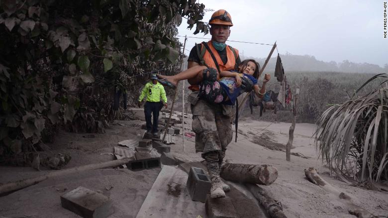 epa06784018 A Guatemalan rescue team worker carries a girl in El Rodeo, Escuintla, Guatemala, 03 June 2018, after the eruption at Fuego volcano, which has left at least 25 dead, around 20 injured and more than 1.7 million people were affected. EPA-EFE/NOE PEREZ