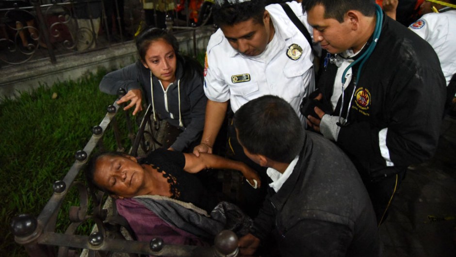EDITORS NOTE: Graphic content / A woman is attended by firefighters after hearing a relative is among the victim's bodies at a morgue in Alotenango municipality, Sacatepequez department, about 65 km southwest of Guatemala City, after the eruption of Fuego Volcano on June 3, 2018. - At least 25 people were killed, according to the National Coordinator for Disaster Reduction (Conred), when Guatemala's Fuego volcano erupted Sunday, belching ash and rock and forcing the airport to close. (Photo by ORLANDO ESTRADA / AFP) (Photo credit should read ORLANDO ESTRADA/AFP/Getty Images)