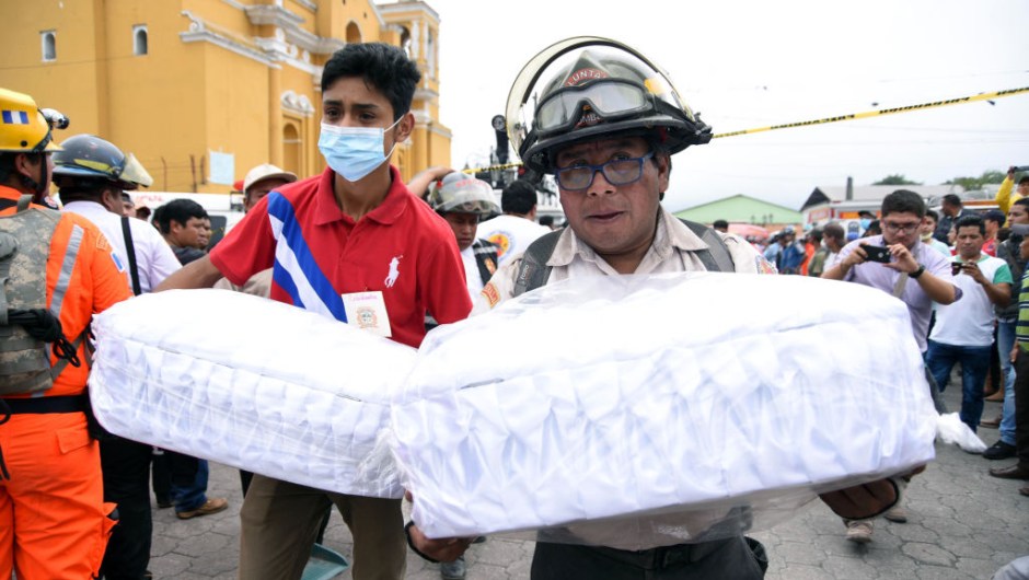 Volunteer firefighters carry to the morgue the coffins with the remais of two children, who died following the eruption of the Fuego volcano, in Alotenango municipality, Sacatepequez, about 65 km southwest of Guatemala City, on June 4, 2018. - Rescue workers Monday pulled more bodies from under the dust and rubble left by an explosive eruption of Guatemala's Fuego volcano, bringing the death toll to at least 62. (Photo by ORLANDO ESTRADA / AFP) (Photo credit should read ORLANDO ESTRADA/AFP/Getty Images)