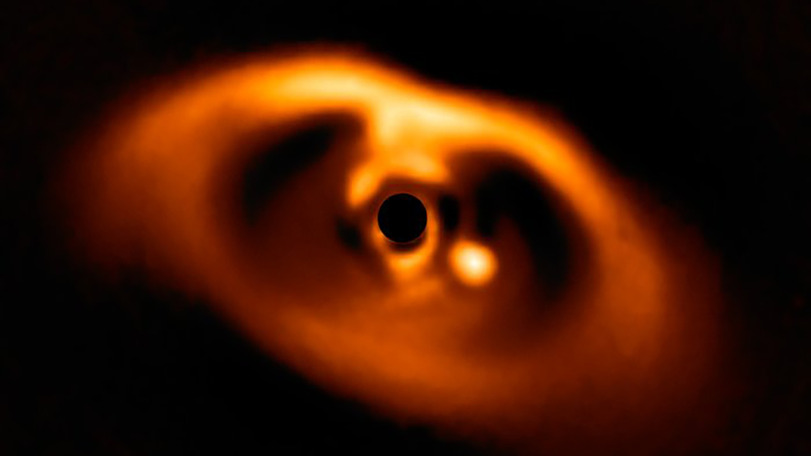 This spectacular image from the SPHERE instrument on ESO's Very Large Telescope is the first clear image of a planet caught in the very act of formation around the dwarf star PDS 70. The planet stands clearly out, visible as a bright point to the right of the centre of the image, which is blacked out by the coronagraph mask used to block the blinding light of the central star.