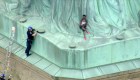 Una mujer trepa la Estatua de la Libertad