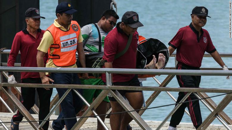 Thai rescue personnel carry a body bag bearing the recovered body of a passenger from a capsized tourist boat at Chalong pier in Phuket on July 6, 2018. - Dozens of passengers are missing after a boat capsized as high winds whipped up rough seas off the Thai tourist island of Phuket, officials said late July 5. (Photo by Mohd RASFAN / AFP) (Photo credit should read MOHD RASFAN/AFP/Getty Images)