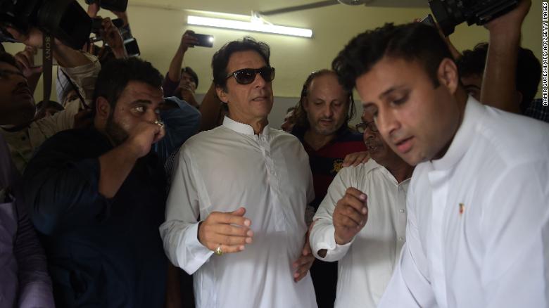 El jugador de críquet paquistaní convertido en político, Imran Khan, llega a una mesa de votación para emitir su voto.
