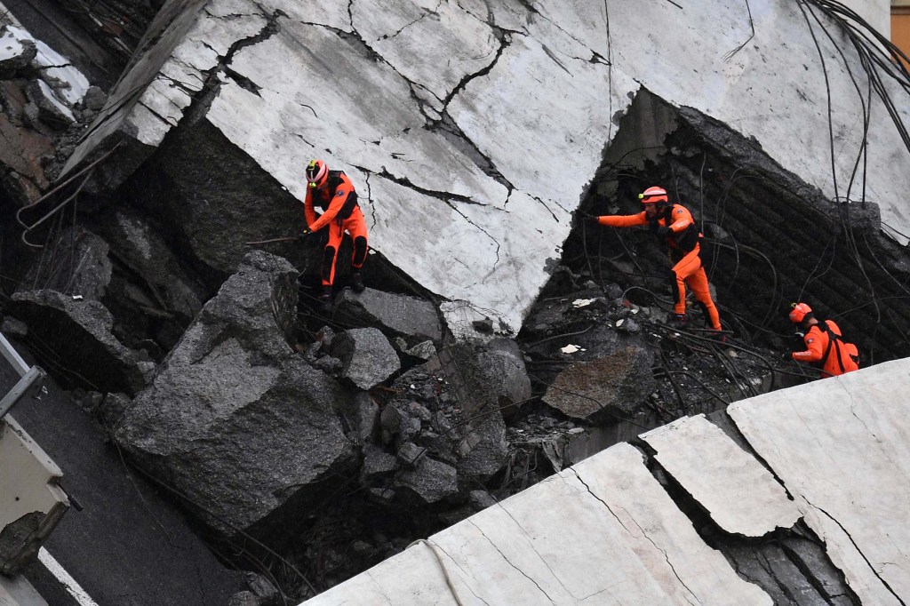 epa06948887 Rescuers at work amid the rubble after a highway bridge collapsed in Genoa, Italy, 14 August 2018. A large section of the Morandi viaduct upon which the A10 motorway runs collapsed in Genoa on Tuesday. Several people have died, rescue sources said. Several vehicles were crushed under the rubble with dead people inside, the sources said. EPA-EFE/LUCA ZENNARO
