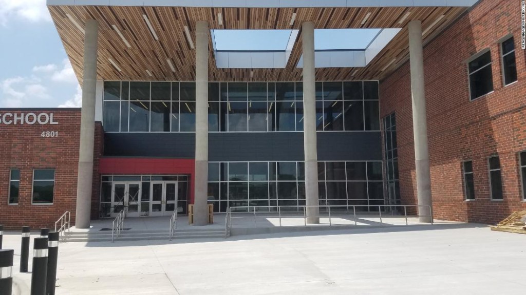La entrada a esta escuela secundaria, diseñada por PBK / IN2 Architecture, incluye grandes ventanas de vidrio, postes de protección y una entrada claramente delineada en rojo.