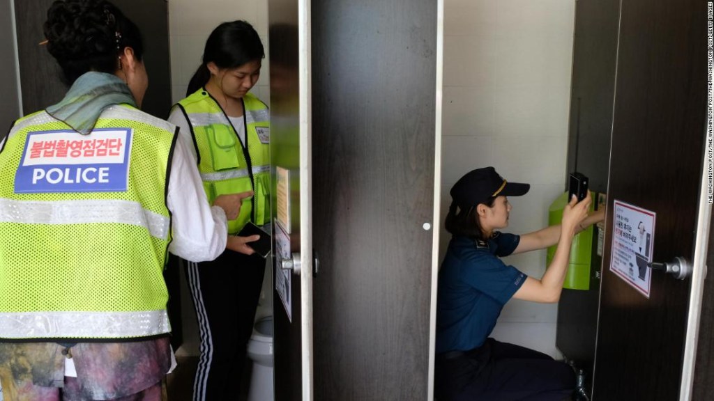 Un escuadrón de búsqueda de cámara oculta, formado por voluntarios estudiantes y ciudadanos, escanea un baño cerca de una piscina pública en Changwon, Corea del Sur, el 25 de julio de 2018.
