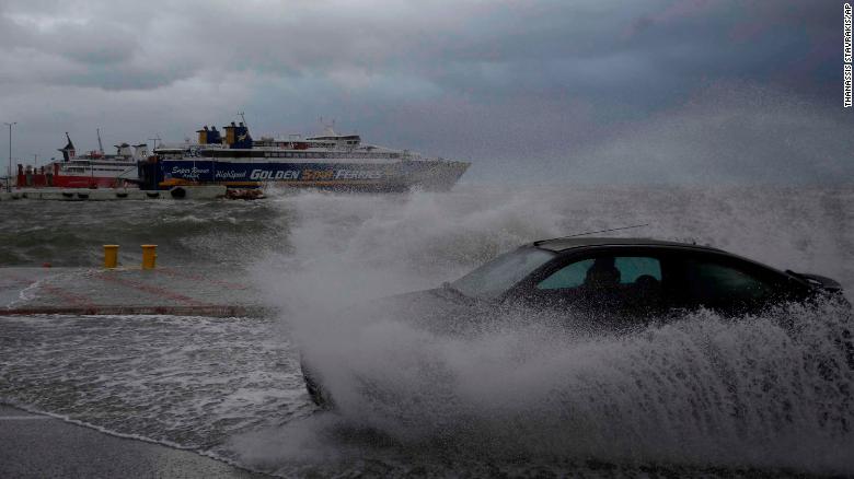 A car drives through seawater from crashing waves on the road during bad weather at the port of Rafina, east of Athens, on Thursday, Sept. 27, 2018. Severe weather warnings remain in effect around Greece, halting ferry services and prompting school closures. (AP Photo/Thanassis Stavrakis)