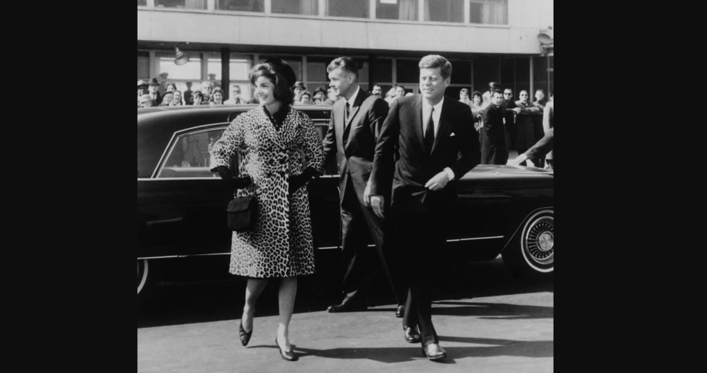 Escoltada por el presidente Kennedy, Jacqueline Kennedy sale para un viaje a India y Pakistán con un abrigo de piel de leopardo Oleg Cassini en 1962. (Crédito: Cortesía de la colección Everett)