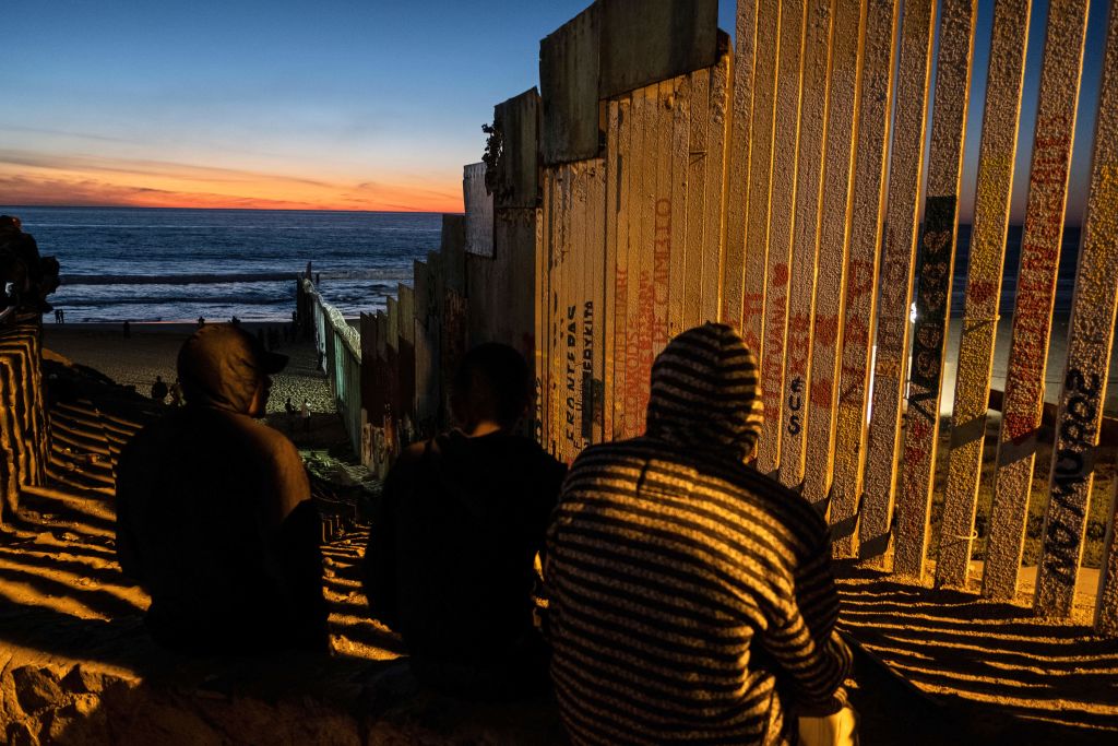 TOPSHOT - Central American migrants moving towards the United States in hopes of a better life, are seen near the US-Mexico border fence in Playas de Tijuana, Mexico, on November 14, 2018. - US Defence Secretary Jim Mattis said Tuesday he will visit the US-Mexico border, where thousands of active-duty soldiers have been deployed to help border police prepare for the arrival of a "caravan" of migrants. (Photo by Guillermo Arias / AFP) (Photo credit should read GUILLERMO ARIAS/AFP/Getty Images)