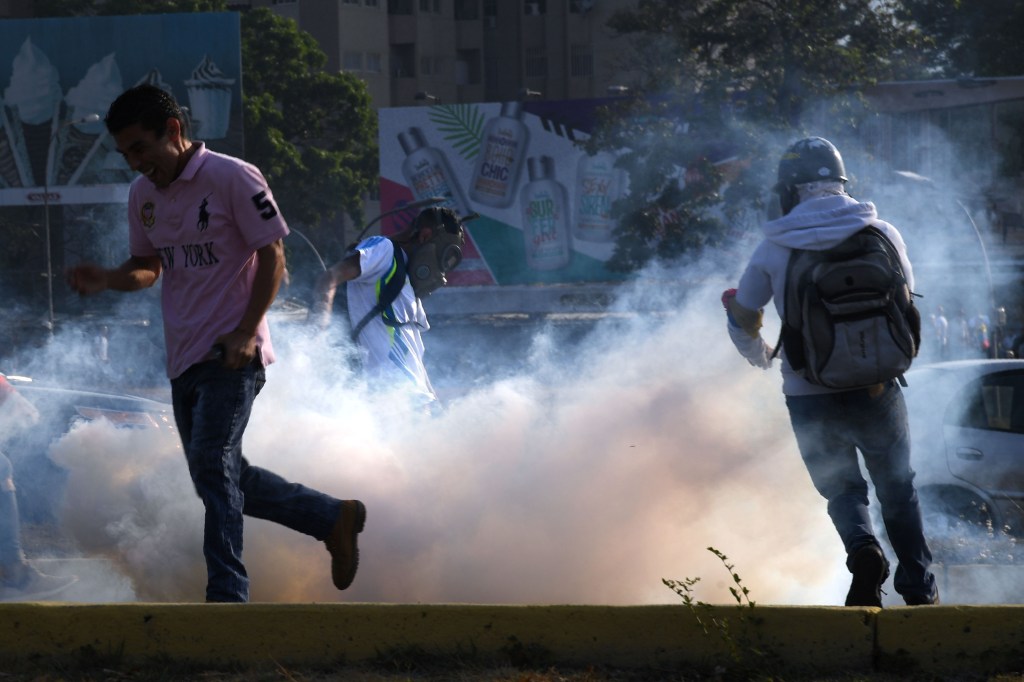 Un grupo de personas huye de los gases lacrimógenos durante los enfrentamientos con las fuerzas de seguridad en Caracas el 30 de abril de 2019. Crédito: YURI CORTEZ / AFP / Getty Images