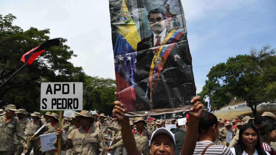 A supporter of Venezuelan President Nicolas Maduro displays a poster of Maduro during a rally on May Day in Caracas on May 1, 2019. - Pro- and anti-government rallies were due to take place in Venezuela, a day after violent clashes erupted in the capital following opposition leader Juan Guido's call on the military to rise up against Maduro, who claimed the insurrection had failed. (Photo by Yuri CORTEZ / AFP) (Photo credit should read YURI CORTEZ/AFP/Getty Images)