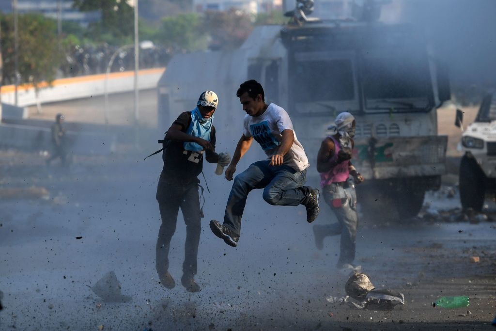 TOPSHOT - Anti-government protesters clash with security forces in Caracas during the commemoration of May Day on May 1, 2019. - Opposition supporters demonstrated for a second consecutive day in support of their country's self-proclaimed leader Juan Guaido as he bids to overthrow President Nicolas Maduro. Maduro and his government have vowed to put down what they see as an attempted coup by the US-backed opposition leader. (Photo by Federico PARRA / AFP) (Photo credit should read FEDERICO PARRA/AFP/Getty Images)