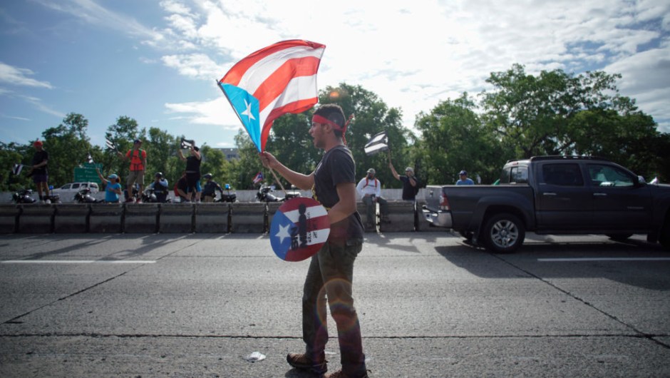 A protester waves the Puerto Rican flag in San Juan, Puerto Rico, July 22, 2019 on day 9th of continuous protests demanding the resignation of Governor Ricardo Rosselló. - Protests erupted last week after the leak of hundreds of pages of text chats on the encrypted messaging app Telegram in which Rossello and 11 other male administration members criticize officials, politicians and journalists. In one exchange, chief financial officer Christian Sobrino makes homophobic references to Latin superstar Ricky Martin. In another, a mocking comment is made about bodies piled up in the morgue after Hurricane Maria, which left nearly 3,000 dead. (Photo by eric rojas / AFP) (Photo credit should read ERIC ROJAS/AFP/Getty Images)